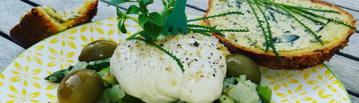 vegane Mozzarella auf Salatbett mit Oliven und knusprigem Brot
